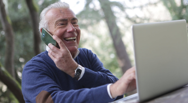 Hombre adulto usando su teléfono móvil y la computadora